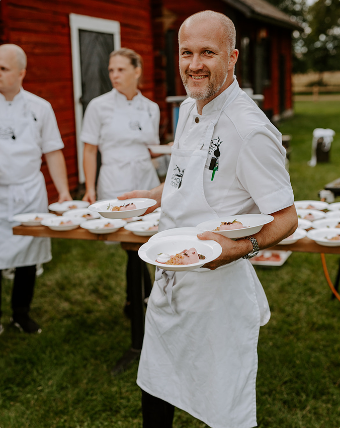 Niklas från Egastronomi bär tallrikar redo att serveras vid catering till bröllop eller event.