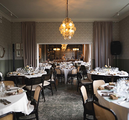 Eleganta runda bord dukade för middag i Egastronomis fest- och konferenslokal med varm belysning.